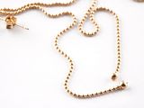 a gold necklace and earring set on a white surface