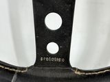 the steering wheel of a car is black and has four holes on it