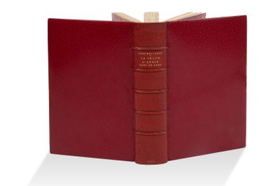 un livre rouge ouvert posé sur une table près d'un mur blanc