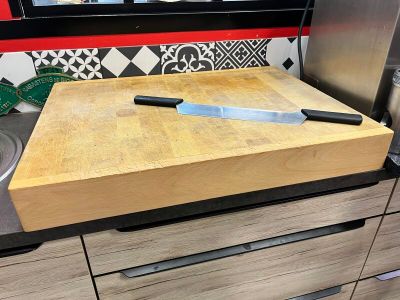 une planche à découper en bois sur laquelle est posé un couteau