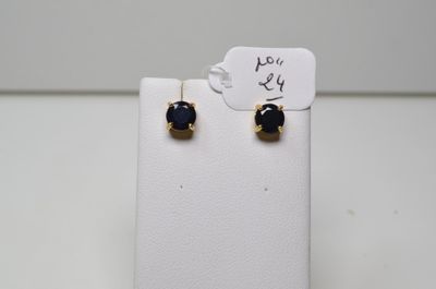 une paire de boucles d'oreilles à clous noires et dorées posées sur un présentoir blanc