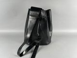 Le petit sac seau noir est posé sur une surface blanche.