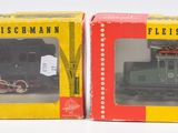 deux boîtes contenant des trains miniatures, posées sur une surface blanche