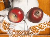 a painting of two apples on a table cloth