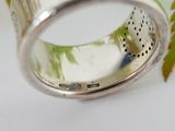 a close up of a ring on a table with a plant in the background