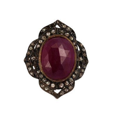 gros plan d'une bague avec une pierre rouge entourée de diamants