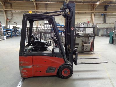 un chariot élévateur rouge dans un entrepôt, à côté d'autres engins