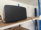 une enceinte noire posée sur une étagère dans une pièce