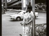 black and white photograph of a woman leaning against a pole next to a dog