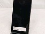a black cell phone sitting on a stand on a white surface