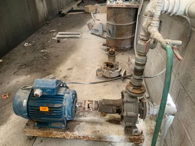 a blue pump on the ground next to a wall