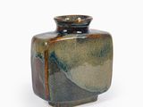 un petit vase posé sur une surface blanche