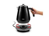 une personne tenant une bouilloire noire au-dessus d'une cafetière électrique