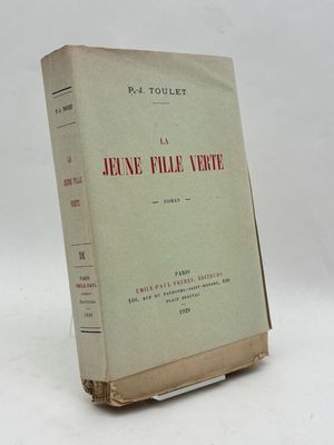 un vieux livre posé sur une table blanche à côté d'un mur blanc