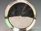 a silver plate on a stand on a white surface