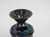 a black and blue vase sitting on top of a white table