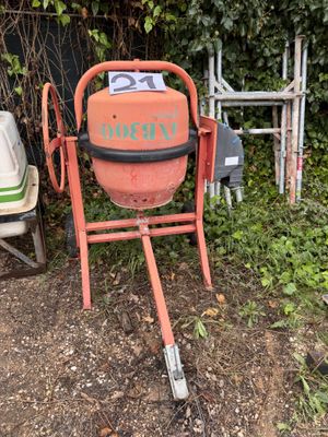 a cement mixer sitting in the yard next to a chair