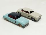 two toy cars sitting next to each other on a white surface