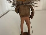 a wooden figurine of a man with a hat and a stick on his head