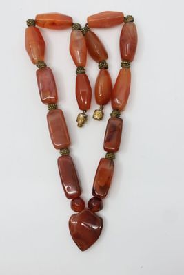 un collier avec un pendentif en forme de cœur et deux perles en cornaline