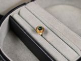 a gold ring with a green stone on it in a case
