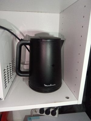 une bouilloire noire posée sur une étagère dans un micro-ondes
