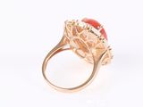 an image of a gold ring with a coral stone in the center