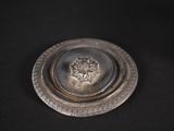an antique silver plate on a black background with a flower in the center
