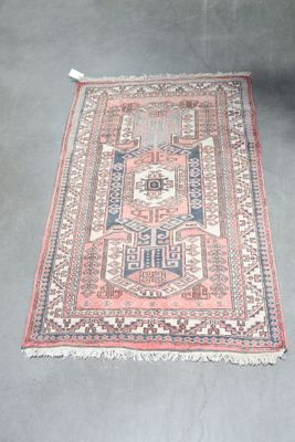 an old rug with a red and blue design on a grey floor