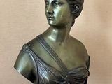 bronze bust of a woman in a dress sitting on a table