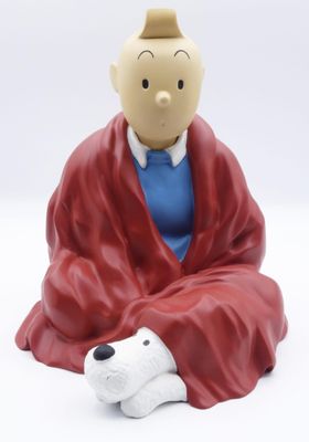 une figurine représentant un homme vêtu d'une robe rouge, assis à côté d'un chien blanc