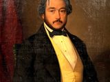 portrait of a man in a tuxedo in a white vest and bow tie