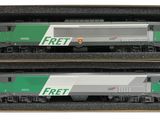 Deux trains miniatures se trouvent dans une boîte posée sur une surface blanche