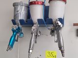 three spray guns hanging on the wall next to each other