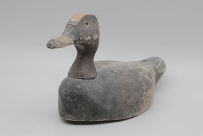 un vieux canard en bois posé sur une surface blanche