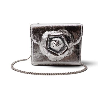 Le porte-monnaie en argent est orné d'une rose sur le devant et d'une chaîne qui l'entoure.