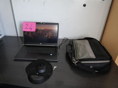 a laptop computer sitting on a desk next to a bag