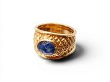 gros plan d'une bague en or avec une pierre bleue