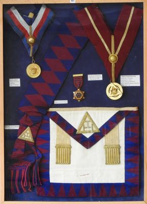 une photo d'un tableau encadré représentant une écharpe maçonnique et des médailles