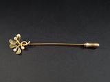 une broche en forme de fleur dorée sur un fond noir