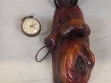 statue of a dog laying down next to a pocket watch on a table