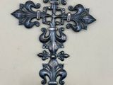une croix en métal accrochée au mur, avec un vase
