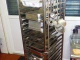 une étagère métallique sur laquelle sont posés de nombreux plats, dans une cuisine