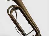 un vieux tuba en laiton est posé sur une surface blanche