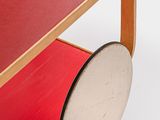 a red table with a wooden base and a white disc on it