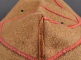 a close up of a brown hat with red stitching on it