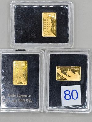 trois lingots d'or sont posés dans des étuis en plastique sur une table