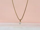 un collier à chaîne en or orné d'un seul diamant sur fond rose