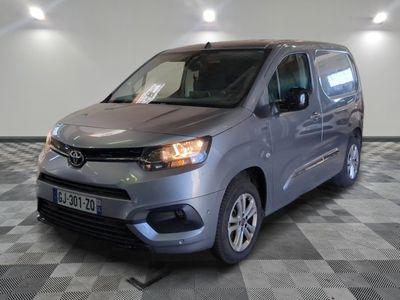 La camionnette argentée est garée dans le garage, sur un sol à damier.