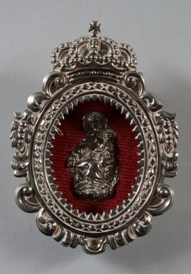 une broche ouvragée, argentée et rouge, surmontée d'une couronne